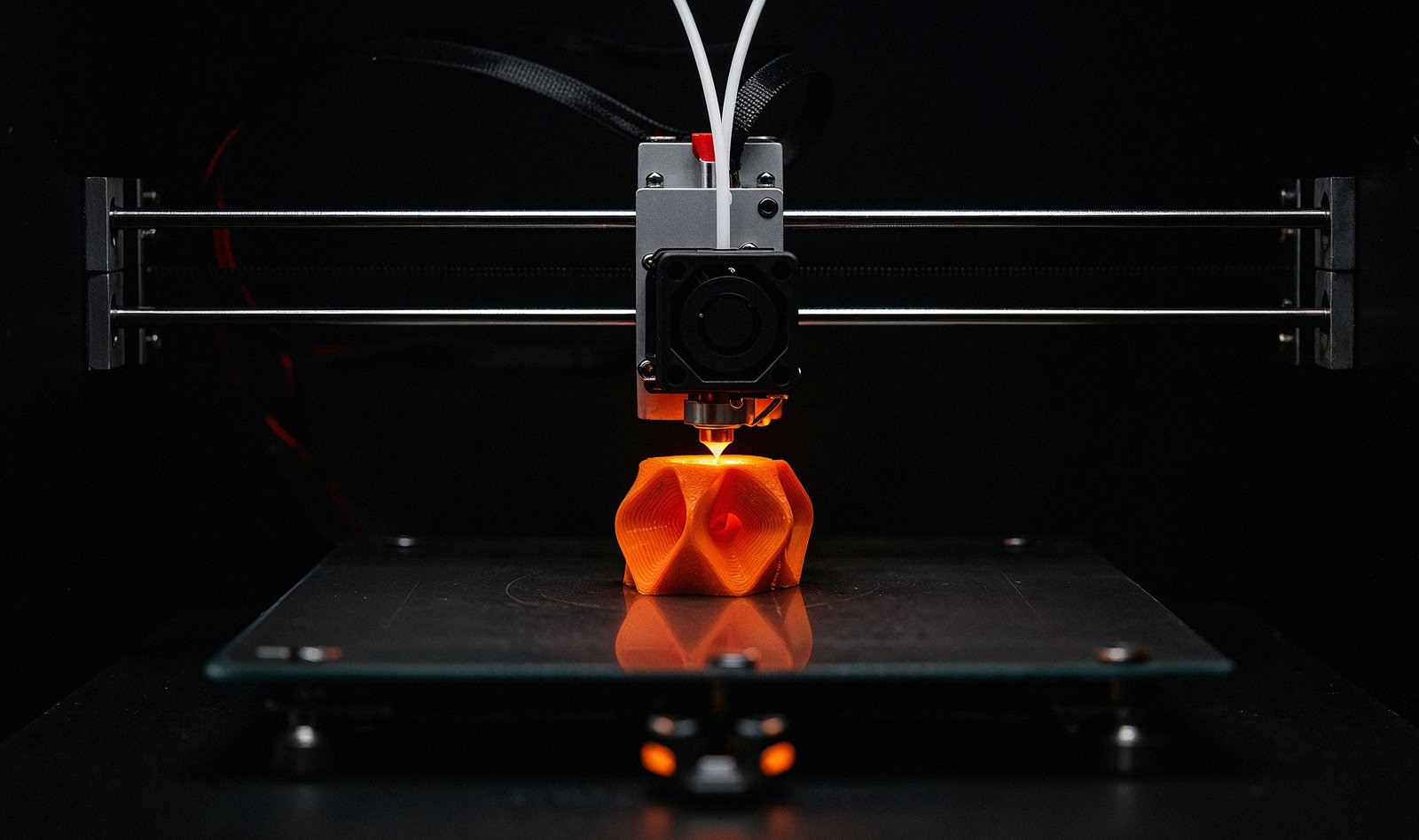 3D printer working on an orange piece